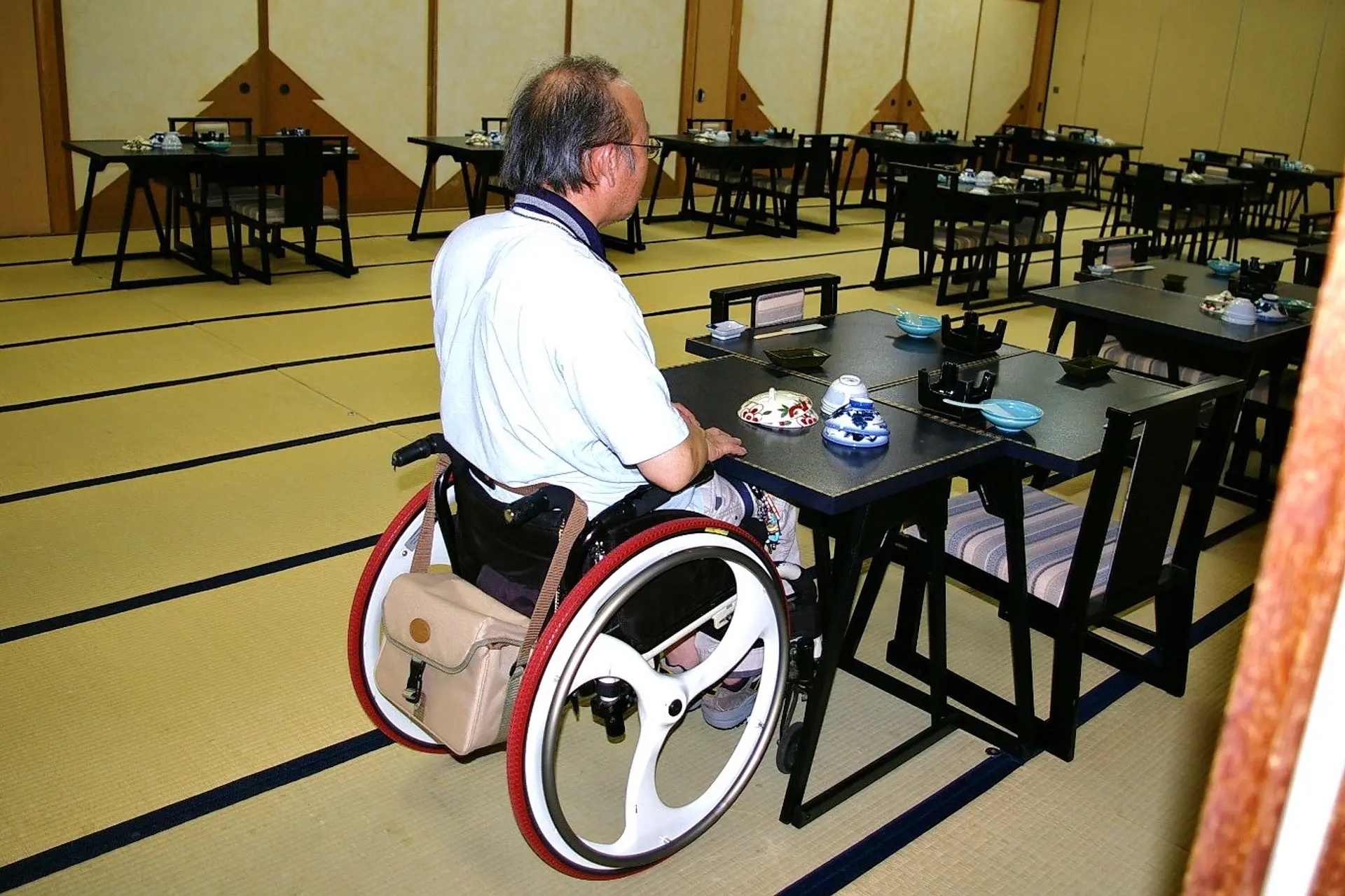 畳の宴会場にテーブル席が用意されていて、車いすの方が席についているようす